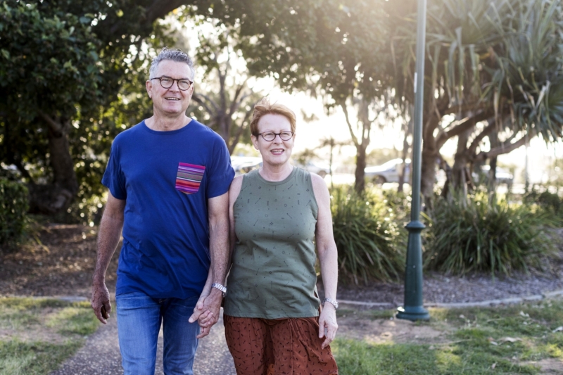 A couple walking in a park holding hands.